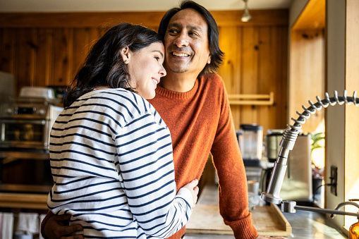 a couple hugs in their kitchen