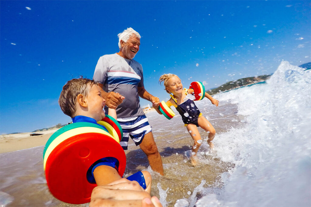 a man plays with his grandchildren at the beach