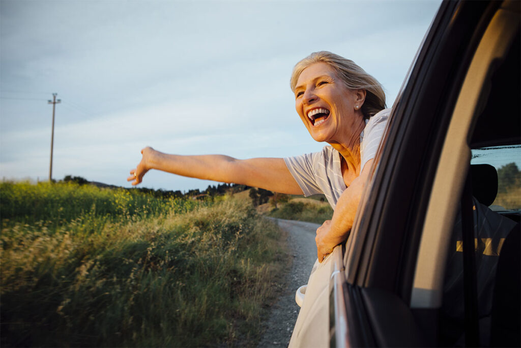 happy elder women smiling with hand out of car