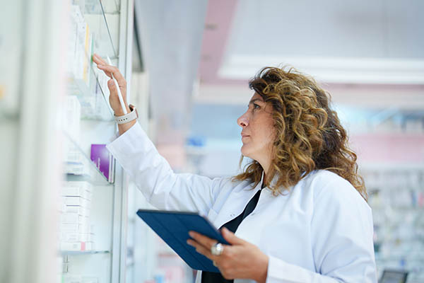 Pharmacist inventorying shelf