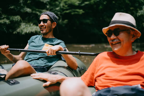 A young man kayaking with and older man on a river