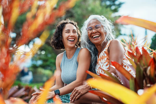 A young woman and an older woman sitting in a garden laughing
