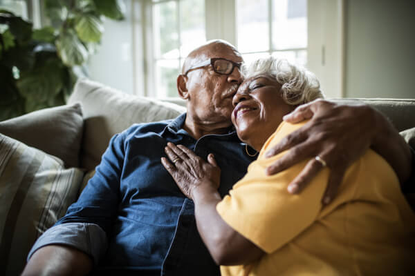 Older couple sitting on the couch relaxing and hugging