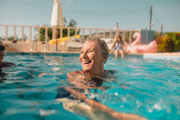 happy older woman swimming in pool in a beautiful day